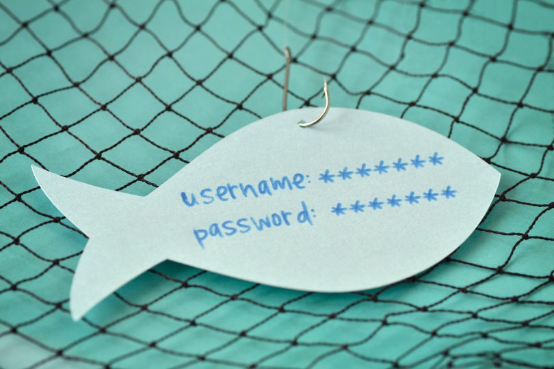 Username and password written on a paper note in the shape of a fish attached to a hook - Phishing and internet security concept