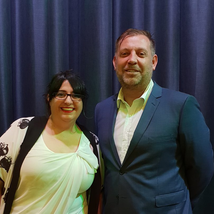 Nadia Pessarossi with Rubik3 founder and senior partner Guy Earnshaw, standing against blue curtain, smiling.