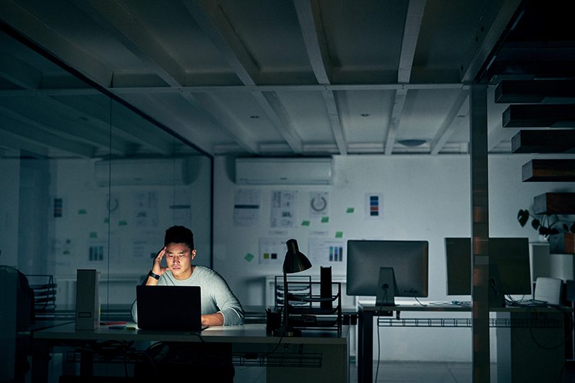 Man sitting alone at computer in room looking concerned.