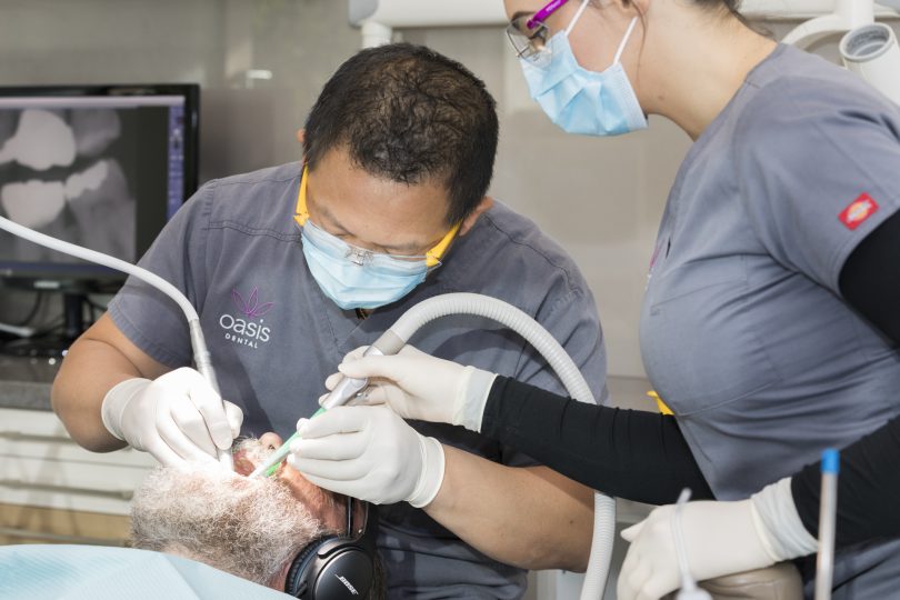 Dr Rick Luu working on patient, with assistant, at Oasis Dental. 