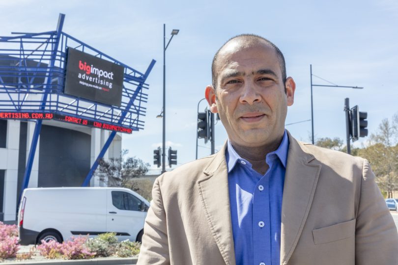 Tam Bakr standing in front of digital billboard.