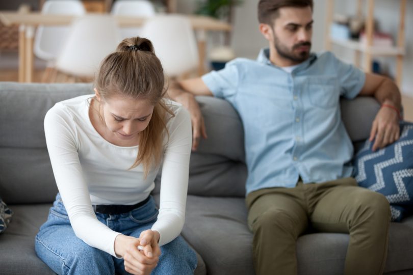 Unhappy married couple sitting on couch.