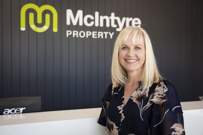 Kellie Chalker-Hall standing in front of McIntyre Property sign.