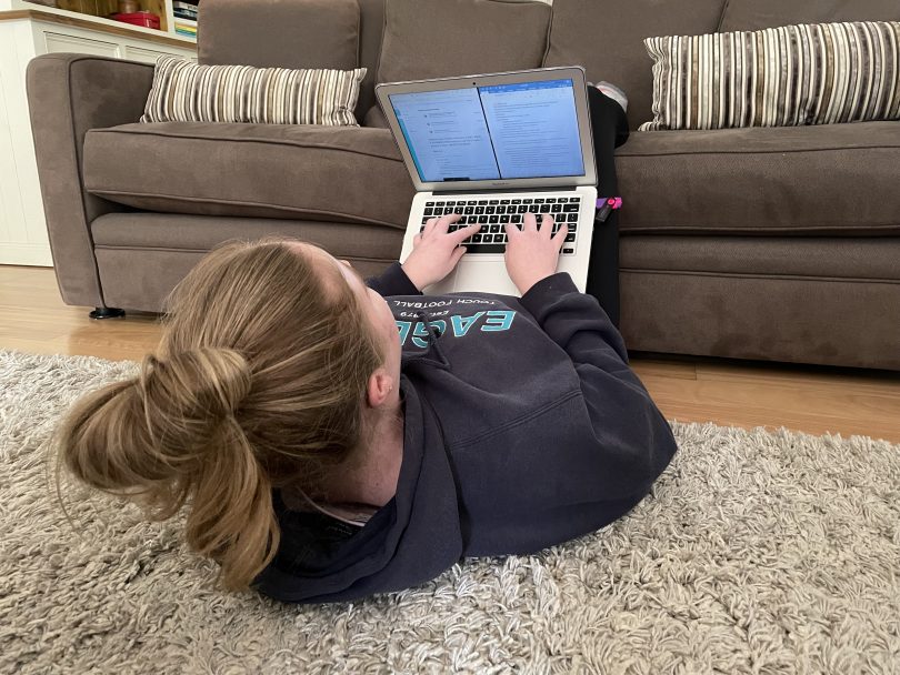 Girl lying down on floor with her laptop and legs on couch