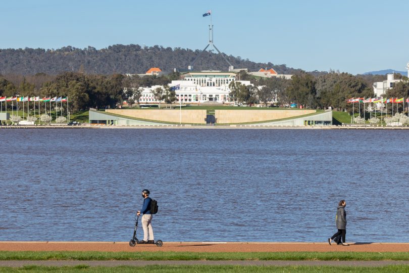 Man riding electric scooter by Lake Burley Griffin