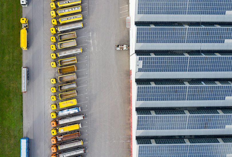 Aerial view of commercial property with trucks lined up and solar panels on roofs