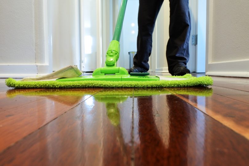 Cleaner mopping a wooden floor at home corridor