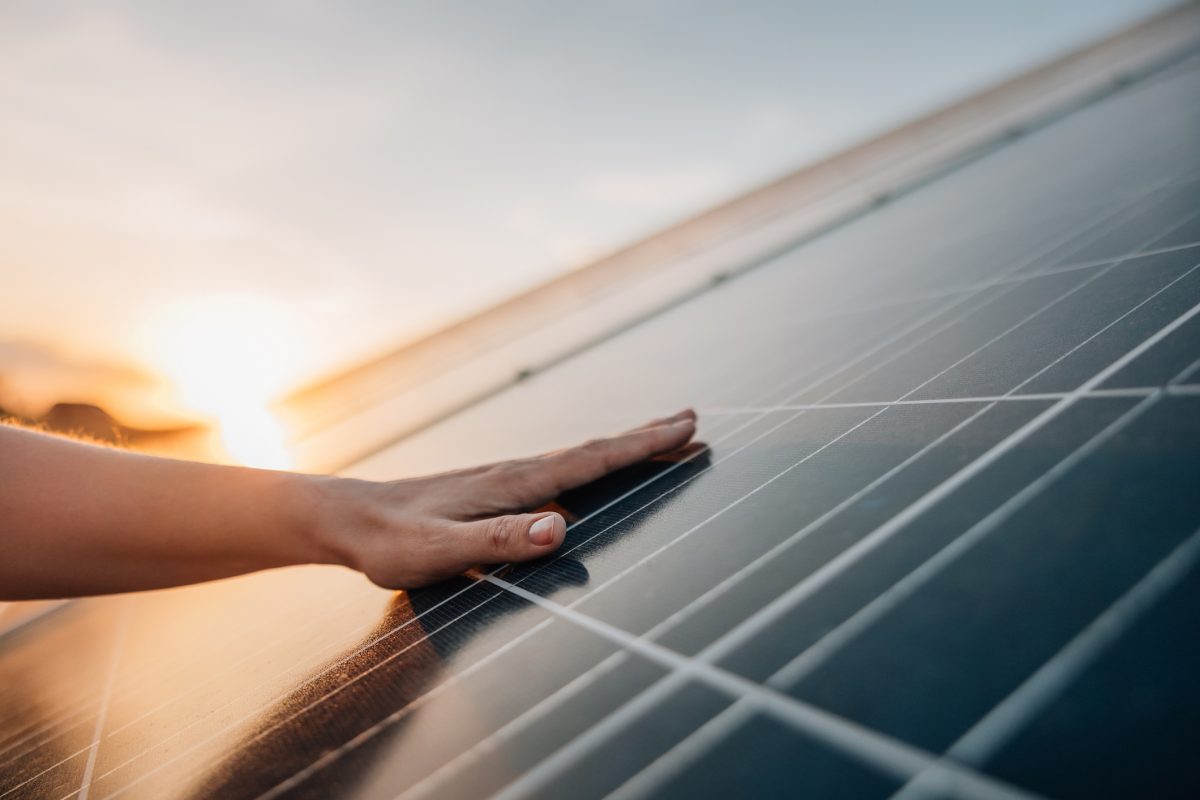 Hand touching solar panels in sunset