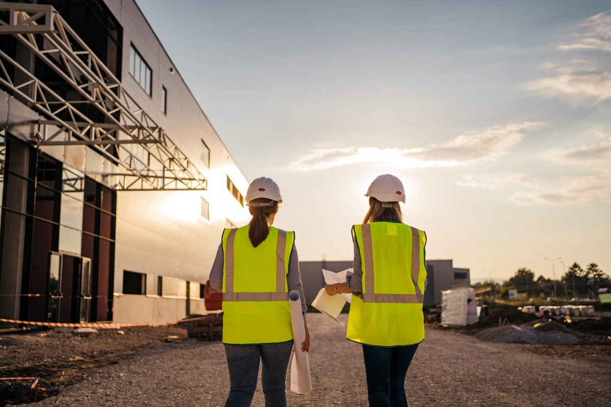 Two women in high vis vests walking through a construction site